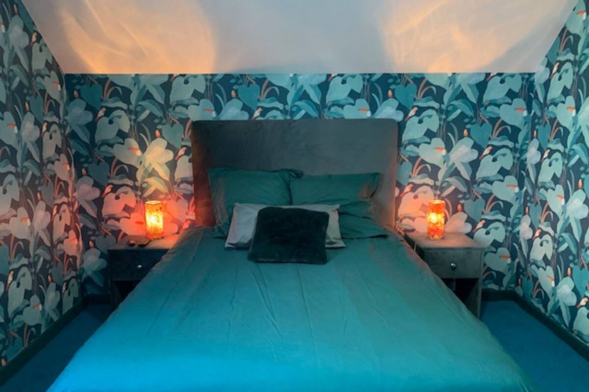A bedroom with a bed, two bedside tables, and floral wallpaper.