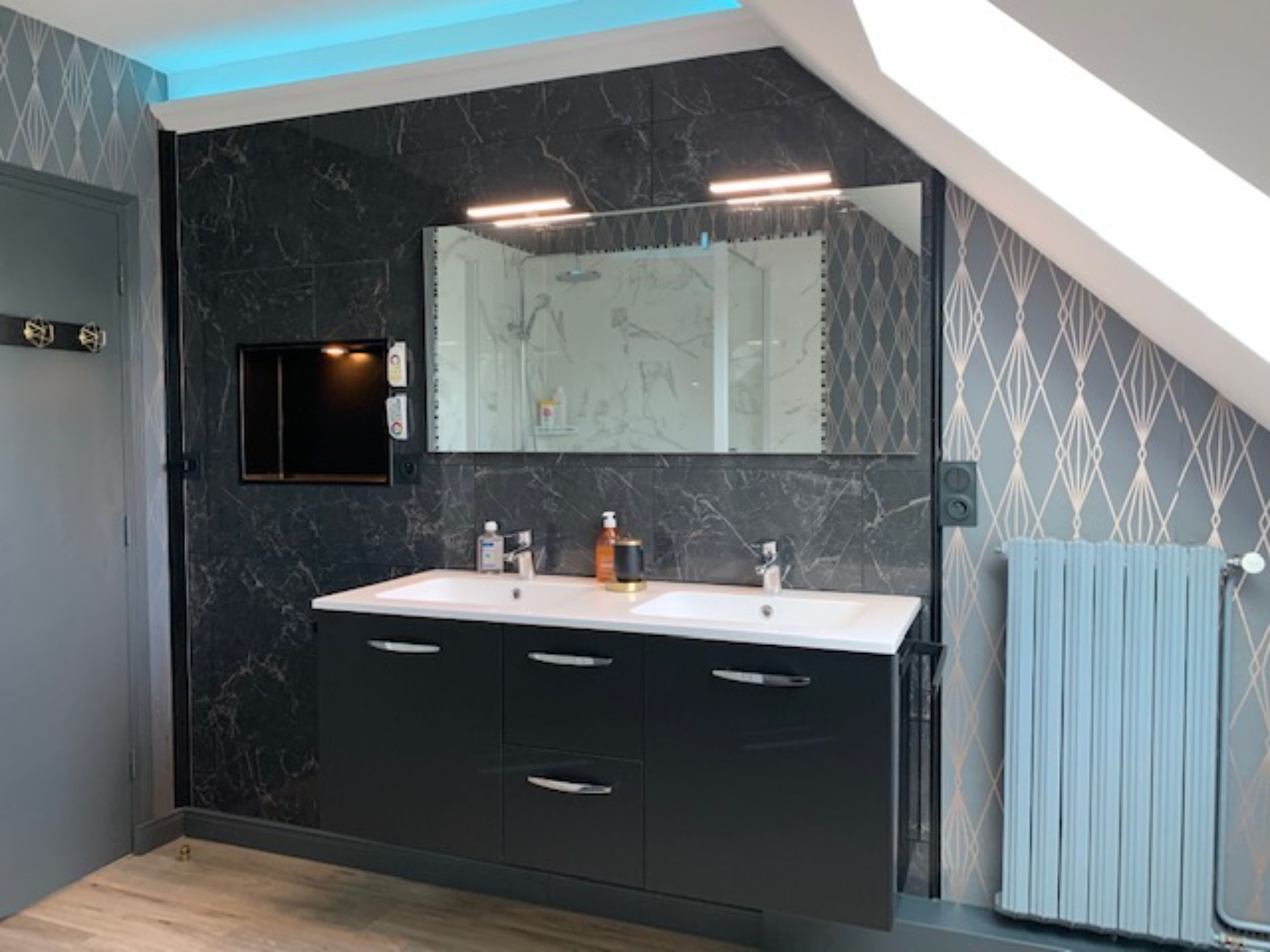 Un baño moderno con un revestimiento de mármol oscuro, un espejo grande y un mueble de tocador doble.