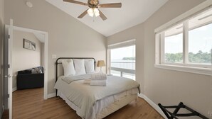 A bedroom with a bed, a ceiling fan, a window, and a view of the outdoors.
