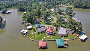 An aerial view of a lakeside community with houses, docks, and a central gazebo-like structure.