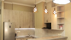 Una cocina moderna con armarios de madera, un refrigerador de acero inoxidable, una isla integrada con taburetes de bar, iluminación colgante y salpicadero.