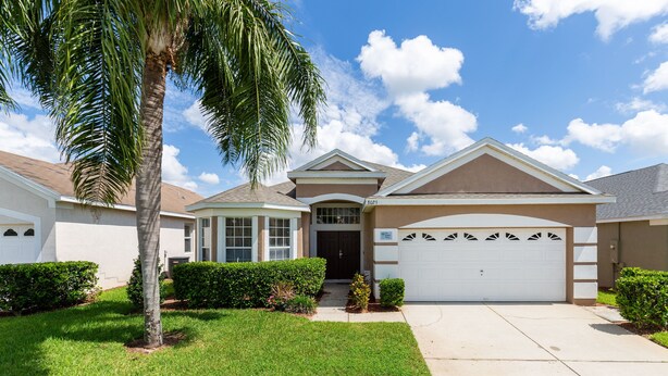 A single-story house with a garage, a front lawn, and a palm tree. - Our Happy Place by VillaDirect (Kissimmee)