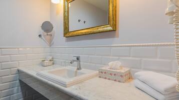 Un baño con un lavamanos de mármol blanco, un espejo con marco dorado y un perchero para toallas.