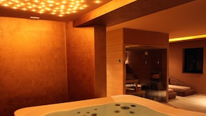 Ein Spa-Raum mit Whirlpool, Holzwänden und einer Glastür zu einem Duschbereich.