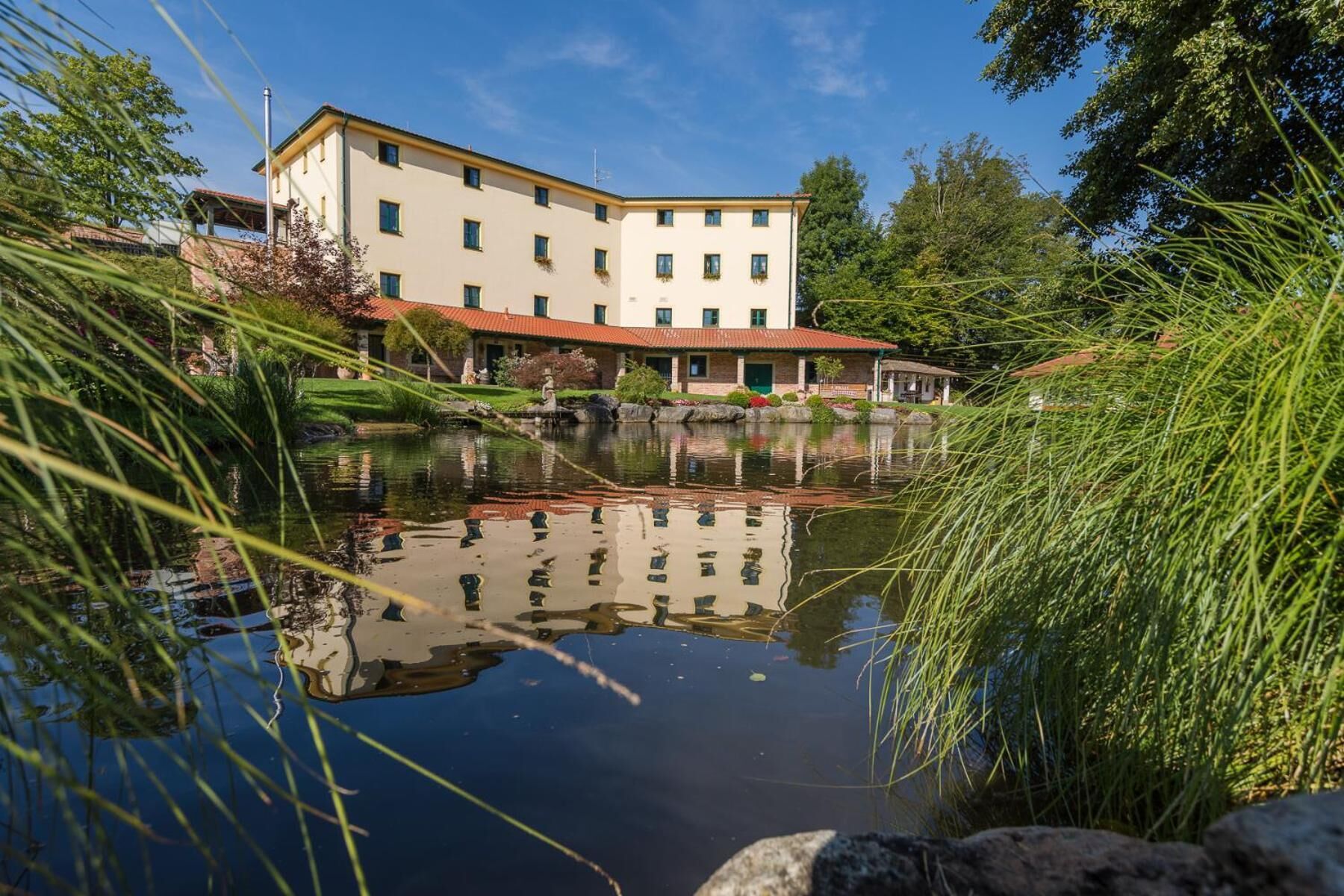 A building with a flat roof, multiple windows, and a reflection in the water.