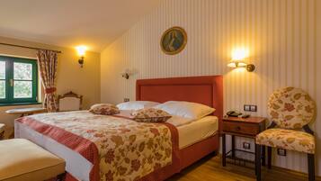 Een slaapkamer met een groot bed, een stoel, een nachtkastje en een wandlamp.