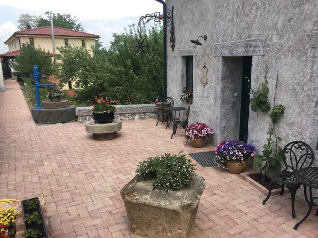 Un cortile con una panchina in pietra, piante in vaso e posti a sedere all'aperto.