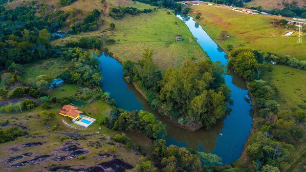 Vista aérea de una propiedad con piscina, río y abundante vegetación.
