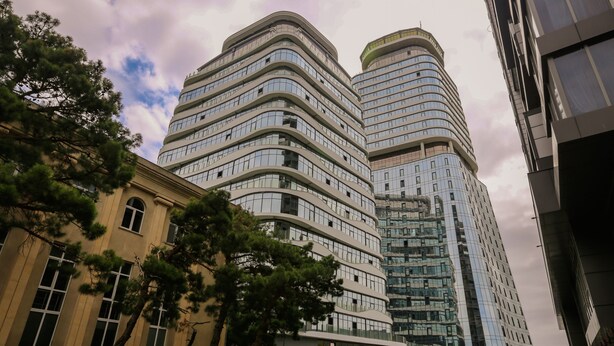 A modern building with a curved facade, large windows, and a reflective glass exterior. - Hosthub - 2BR Super view Apartment (Tbilisi)