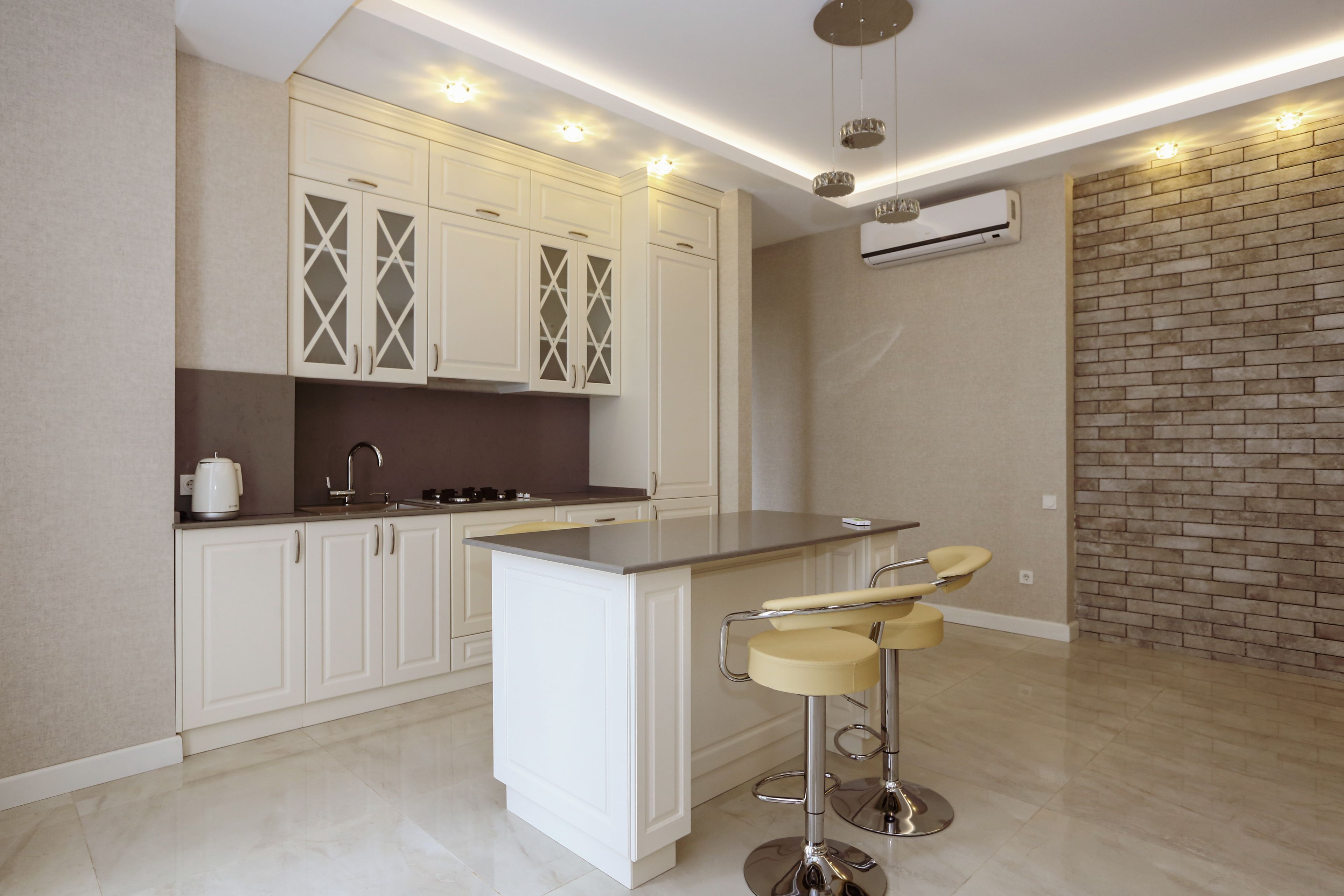 A modern kitchen with white cabinetry, a central island with bar stools, and recessed lighting.