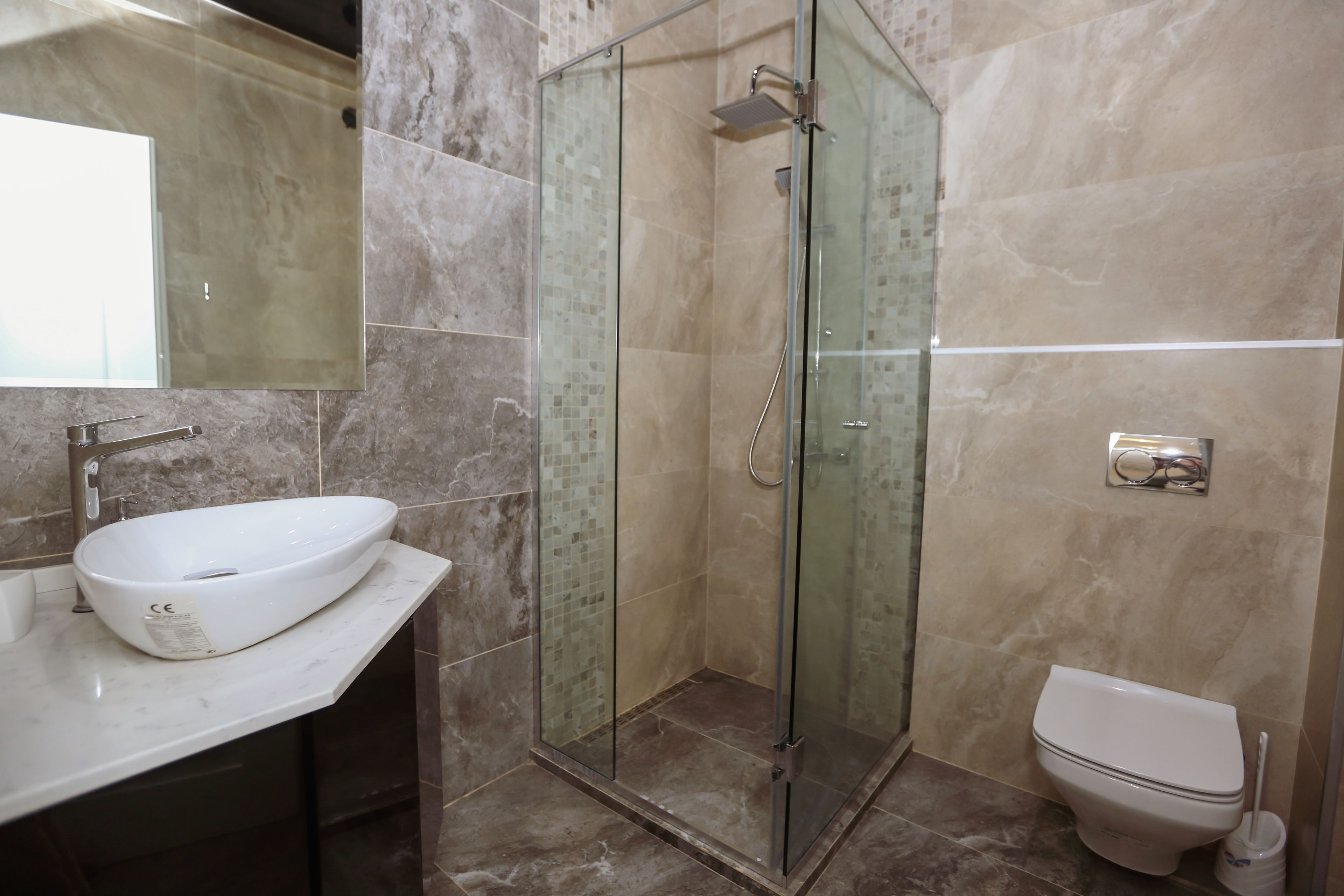 Une salle de bain avec une douche à parois de verre, un lavabo blanc et des toilettes.