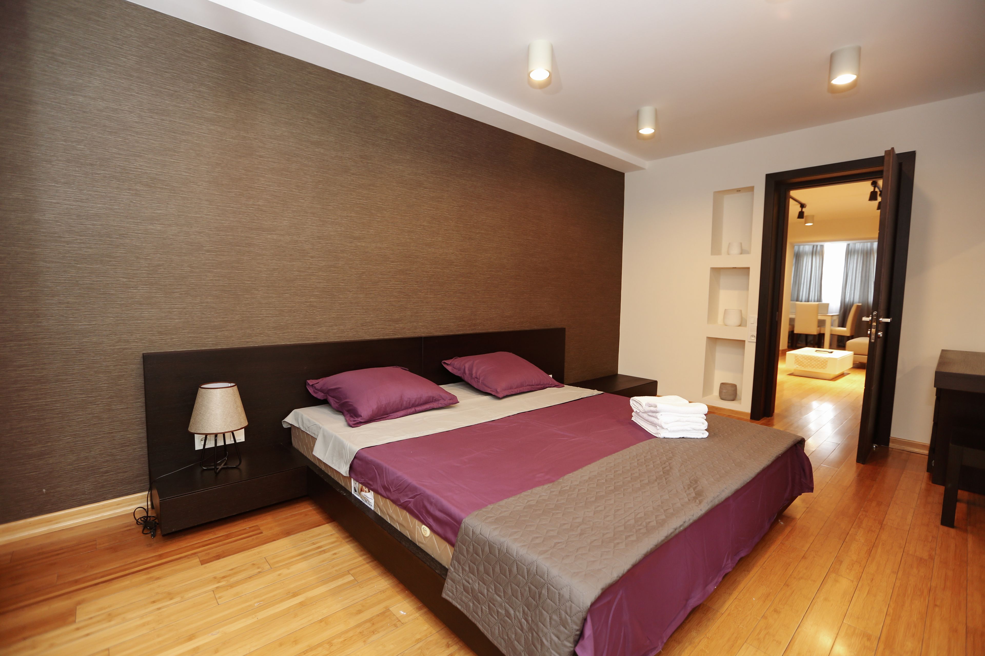 A modern bedroom with a large bed, a bedside table, and a nightstand.
