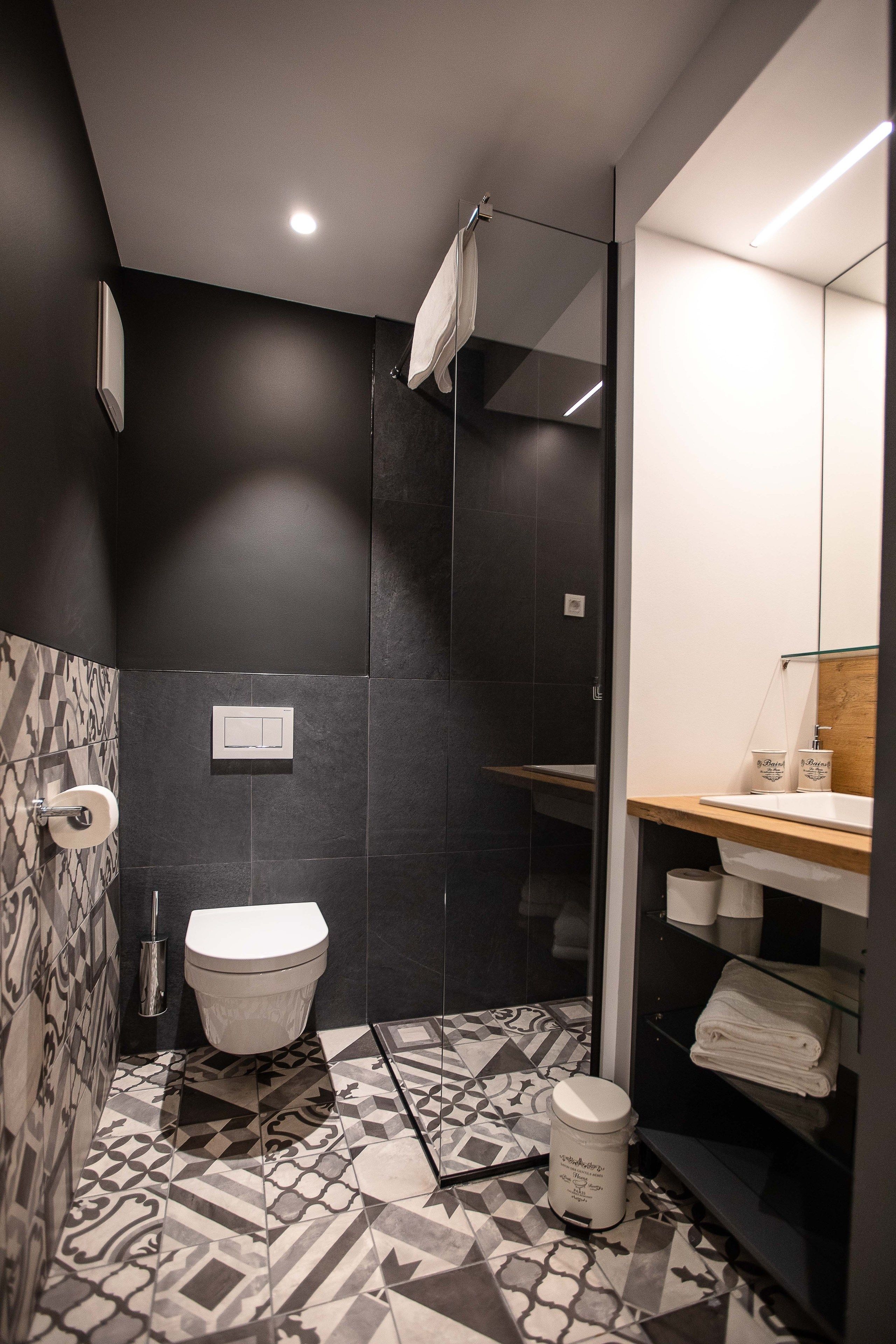 A modern bathroom with a toilet, shower, and sink.