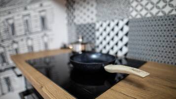 A kitchen with a black induction cooktop, a wooden handle, and a patterned backsplash.
