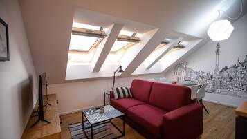 Ett modernt vardagsrum med en röd soffa, ett soffbord och en väggmålning som föreställer en stadsbild.