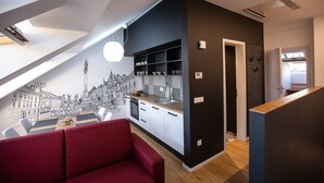 Eine moderne Küche mit Essbereich, ausgestattet mit einem roten Sofa, einem Schwarz-Weiß-Wandgemälde und einer Holz Arbeitsplatte.