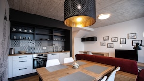 Eine moderne Küche mit weißen Schränken, einem Holztisch und einem roten Sofa.