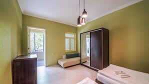 A bedroom with a bed, a dresser, a mirror, and two windows. - City Heart Apartment (Tbilisi)