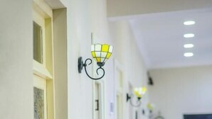A hallway with a series of wall-mounted lights, a door at the end, and a table with chairs in the distance. - City Heart Apartment (Tbilisi)