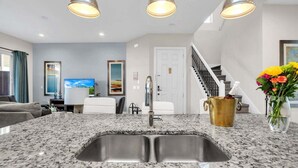 Eine moderne Küche mit Granit Arbeitsplatten, Spüle aus Edelstahl und Pendelleuchten.