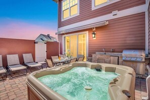 Un jardin avec un jacuzzi, un coin salon extérieur et un barbecue.