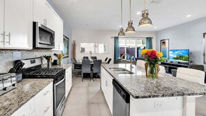 Eine moderne Küche mit Granit-Arbeitsplatten, Edelstahlgeräten und Pendelleuchten.