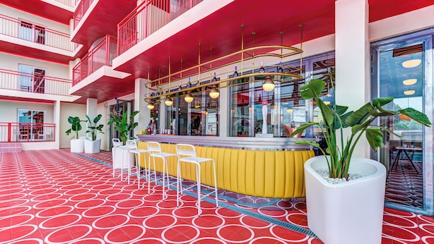 A modern hotel lobby with a red and white color scheme, a central bar area, and potted plants. - Romeos Ibiza - Adults Only (Sant Josep de sa Talaia)