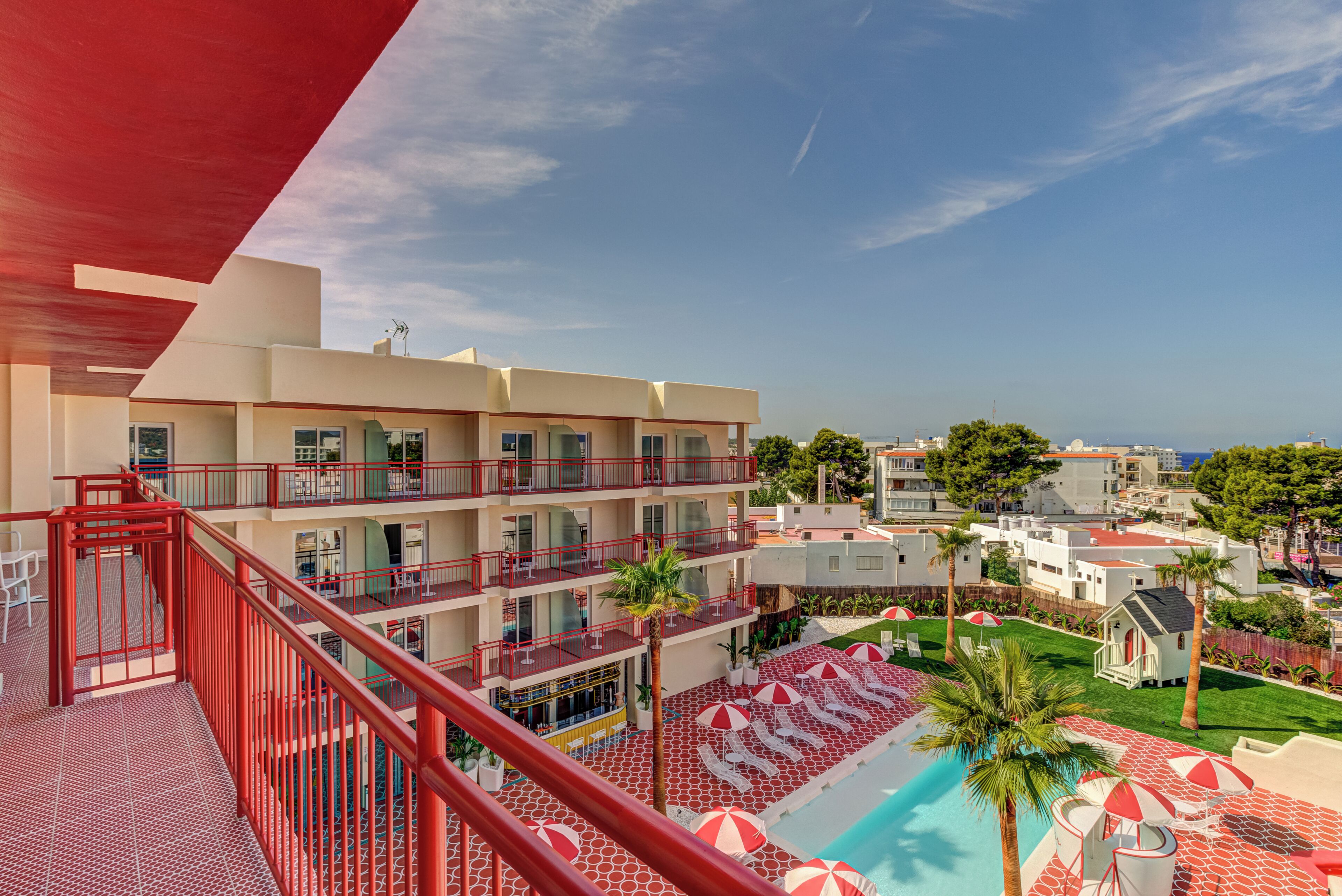 Un hotel con varios pisos, balcones, piscina y vista al mar.