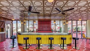 A bar area with a patterned floor, a yellow bar counter, and multiple stools. - Romeos Ibiza - Adults Only (Sant Josep de sa Talaia)