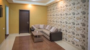A living room with a sofa, a coffee table, and a patterned wallpaper. - Apartment Le Soleil (Tbilisi)