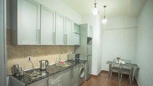 A modern kitchen with stainless steel appliances, a built-in washing machine, and a dining area with a table and chairs. - Apartment Le Soleil (Tbilisi)