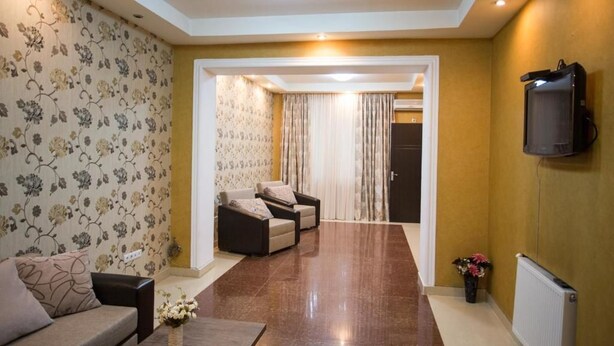 A modern living room with a sofa, two armchairs, a coffee table, and a TV mounted on the wall. - Apartment Le Soleil (Tbilisi)