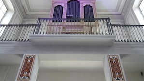 Um interior imponente com varanda, teto ricamente decorado e detalhes arquitetônicos clássicos.