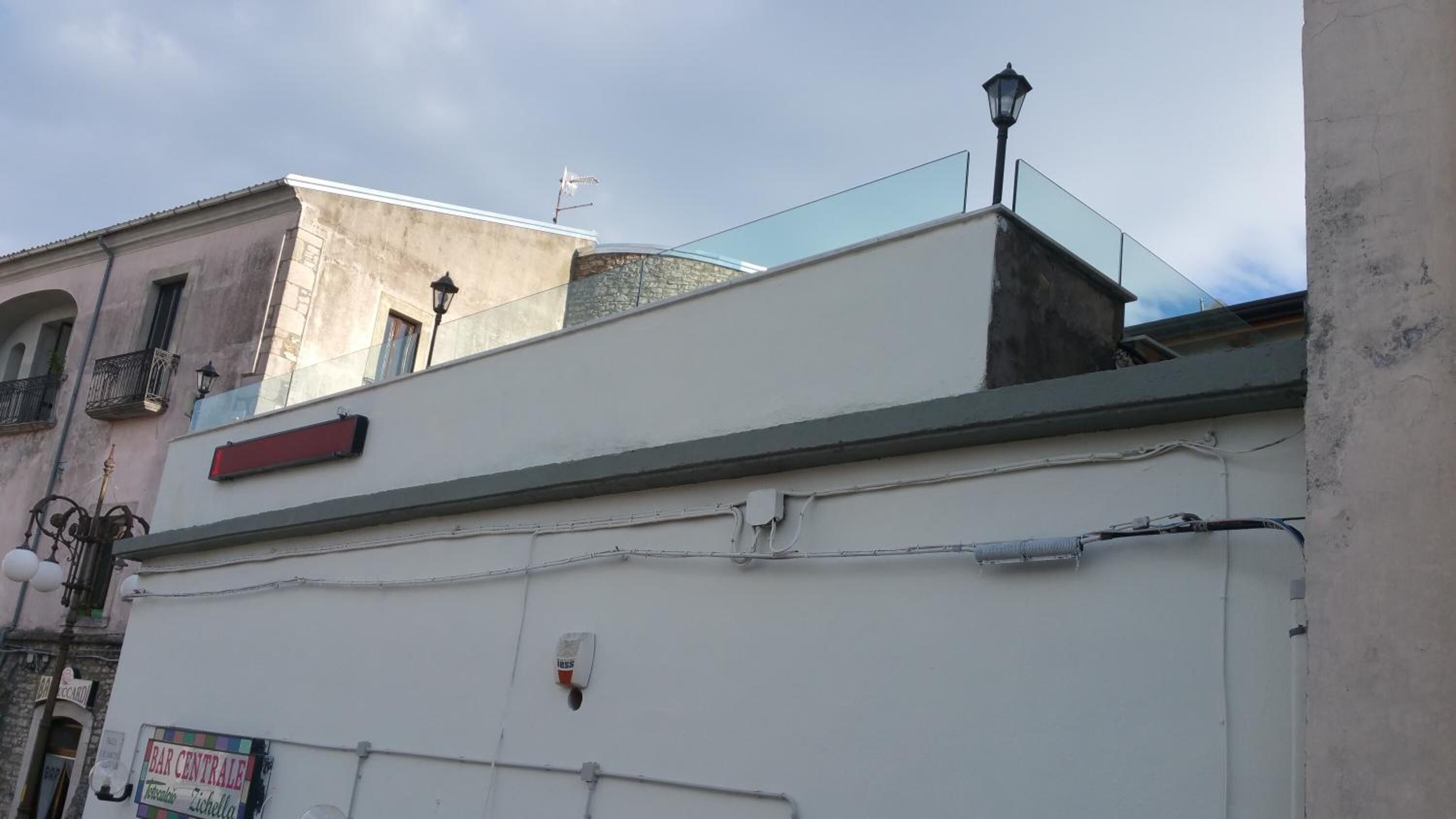 A building with a white facade, a red sign, and a glass balcony.