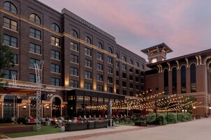 Hotel com fachada de tijolos, várias janelas e área externa coberta com luzes de fada.