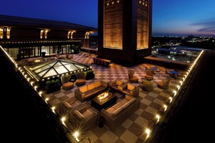 Un espacio al aire libre con piso a cuadros, muebles de mimbre y una chimenea.