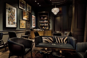 A bar area with leather seating, framed artwork on the walls, and a chandelier. - Hotel Vin, Grapevine, Autograph Collection (Grapevine)
