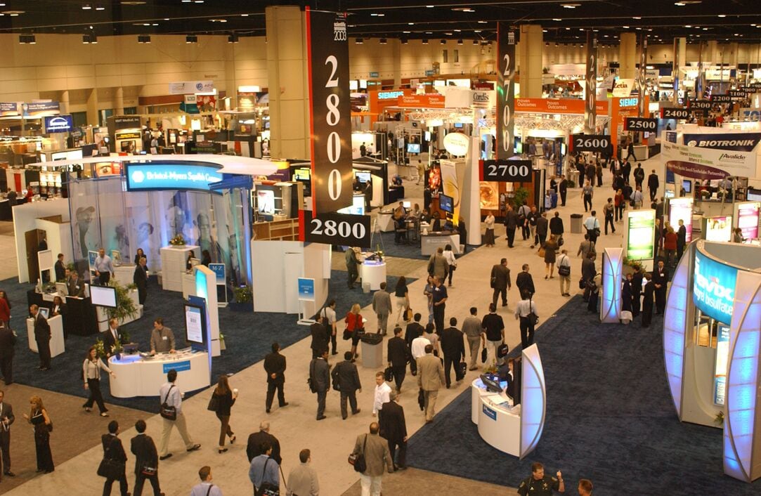 A busy convention center with multiple booths and attendees.