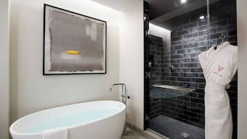 A modern bathroom with a freestanding bathtub, a glass-enclosed shower, and a framed abstract painting on the wall.