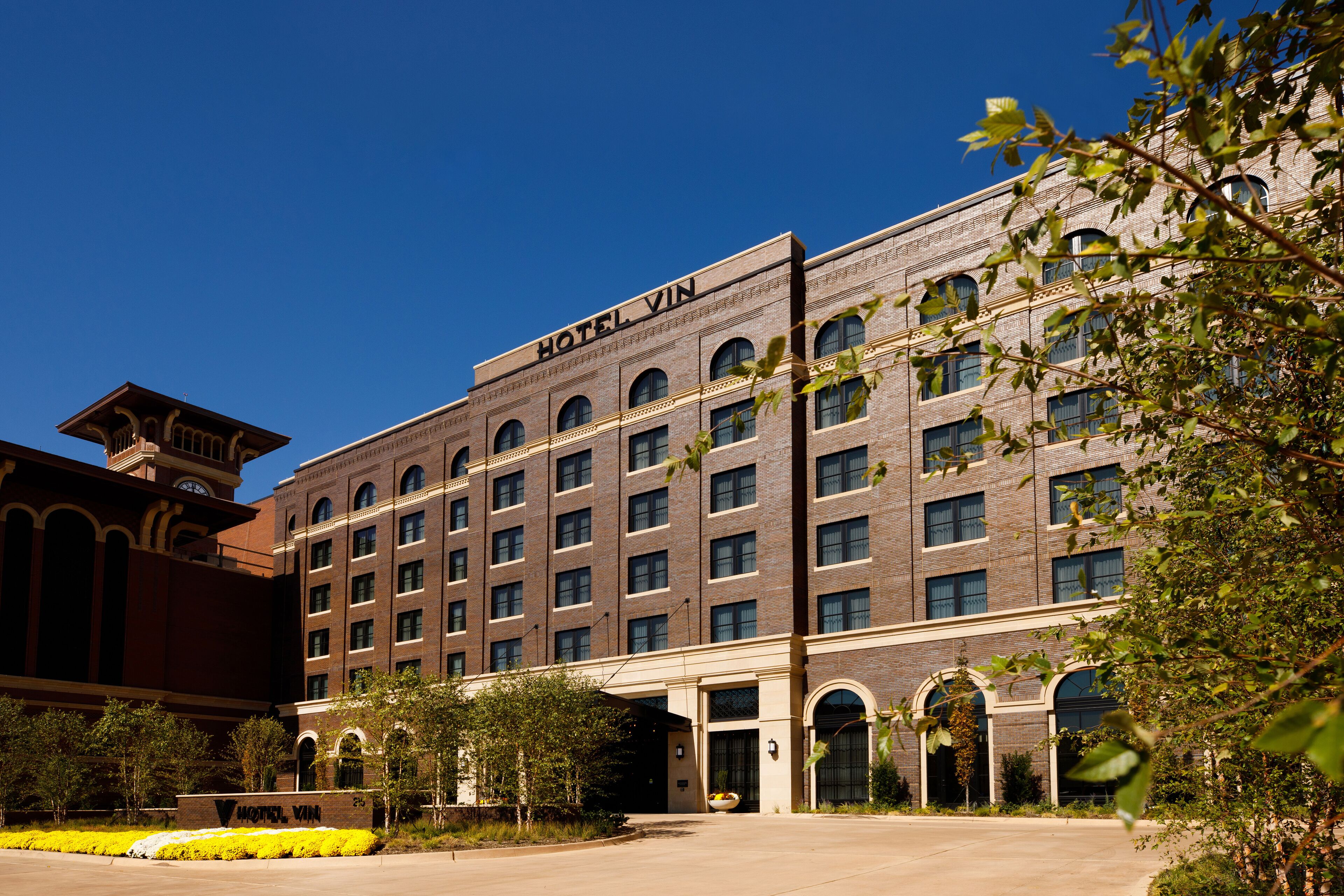 A hotel with a brick facade, multiple windows, and a sign reading "HOTEL VIN".