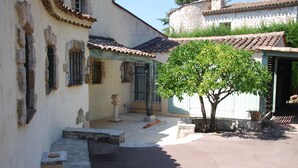 A narrow street with a tree in the center, stone steps leading to a building entrance, and a stone wall in the background. - Provençale charming house  (Mougins)