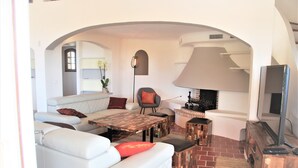 A living room with a white sofa, a coffee table, a fireplace, and a television. - Provençale charming house  (Mougins)