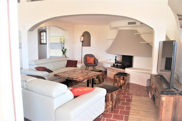 A living room with a white sofa, a coffee table, a fireplace, and a television.