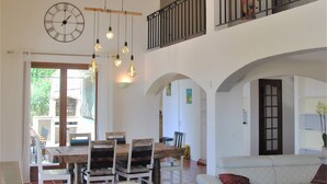 A spacious living area with a high ceiling, exposed beams, and a balcony. There are multiple seating arrangements including a sofa and chairs. - Provençale charming house  (Mougins)