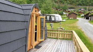 Uma cabana de madeira com telhado inclinado e porta de madeira que dá para um deck.