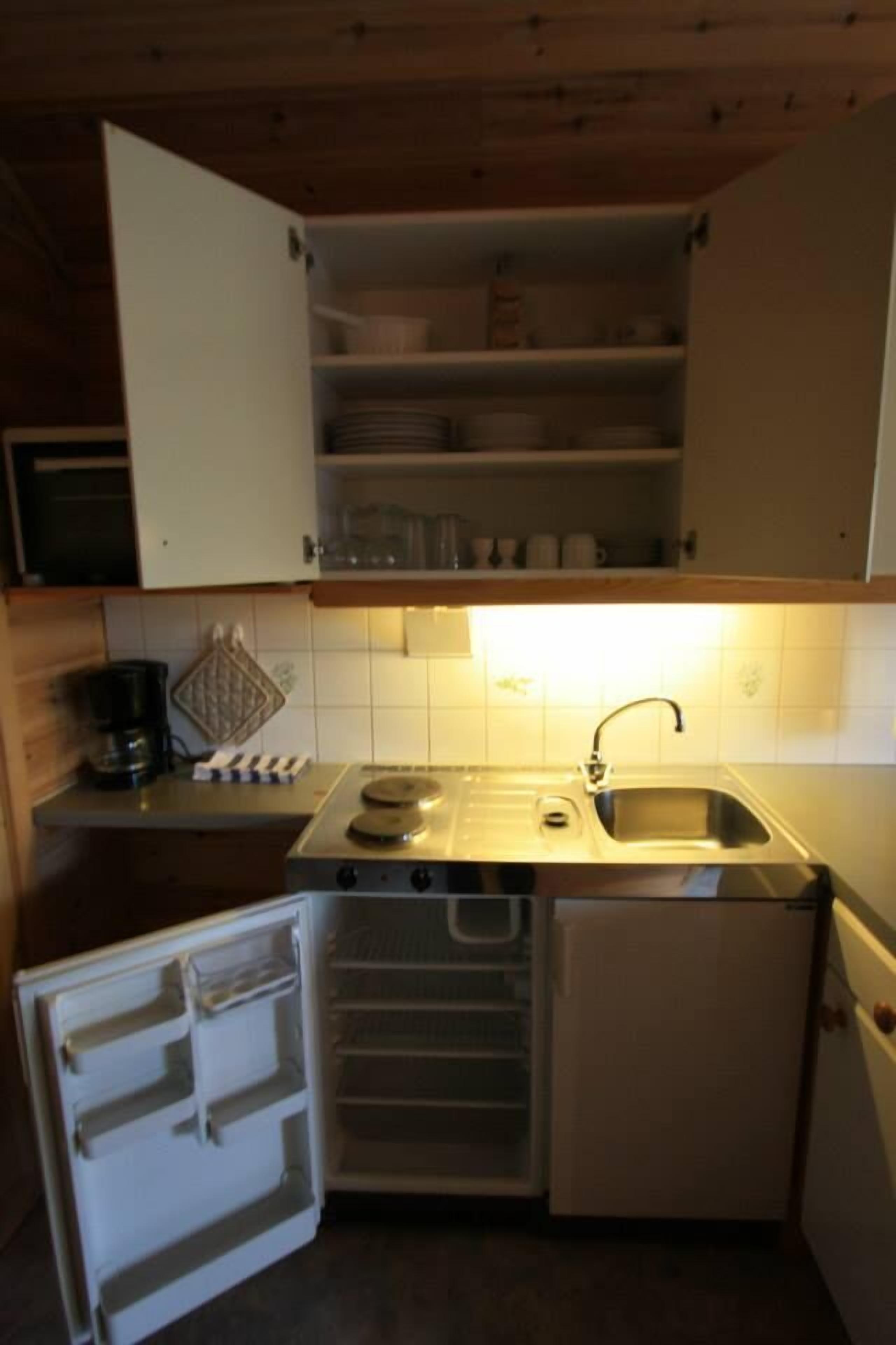 Eine kleine Küche mit Spüle, Herd und Kühlschrank.