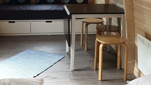 Interior acolhedor em madeira, com uma cama, uma mesa e um banco.