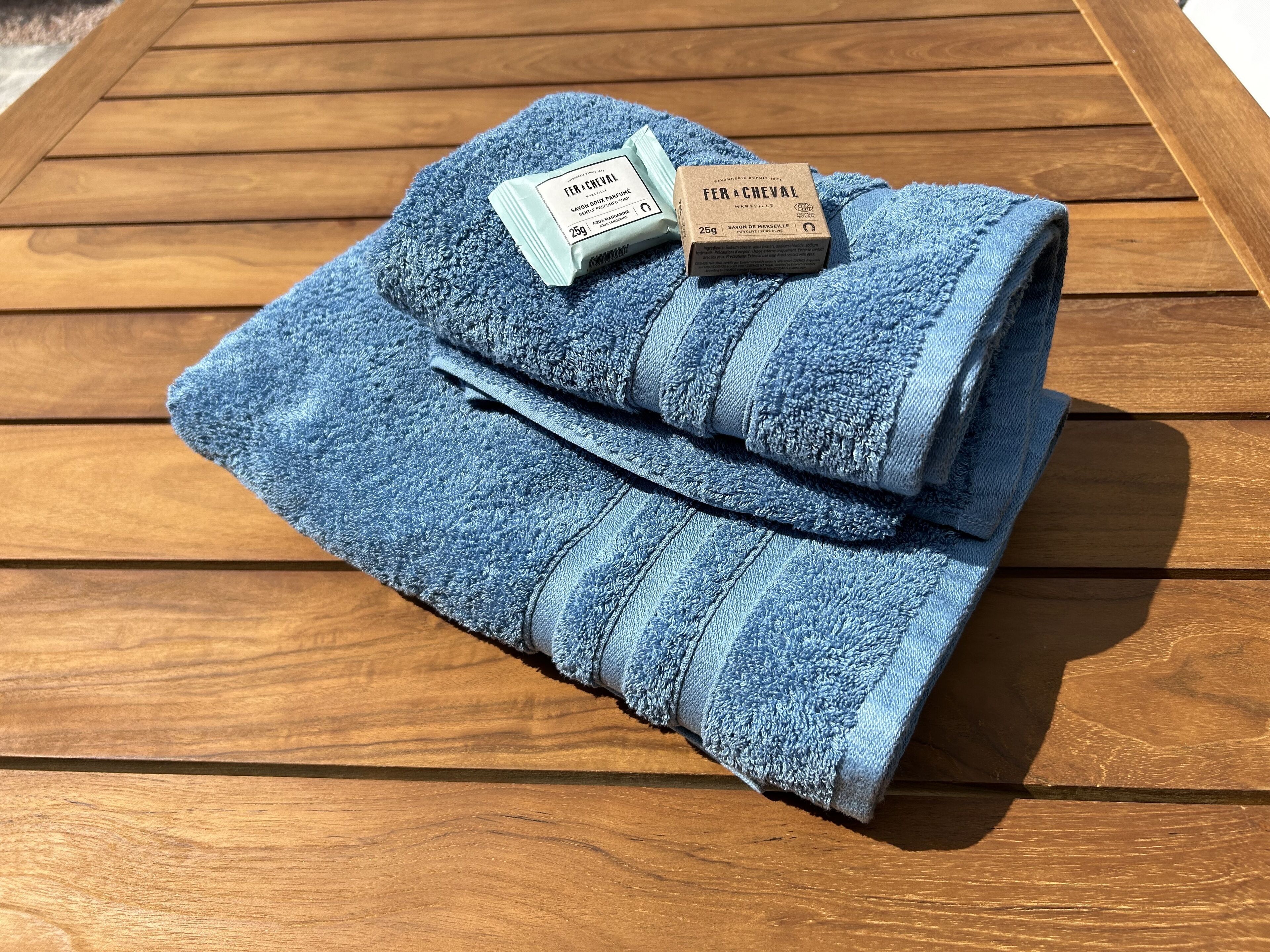 A folded blue towel with a label on it, placed on a wooden surface.