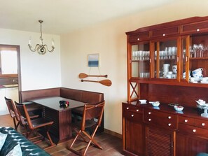 A dining area with a wooden table and chairs, a chandelier, a wooden cabinet with glass doors, and a framed picture on the wall.