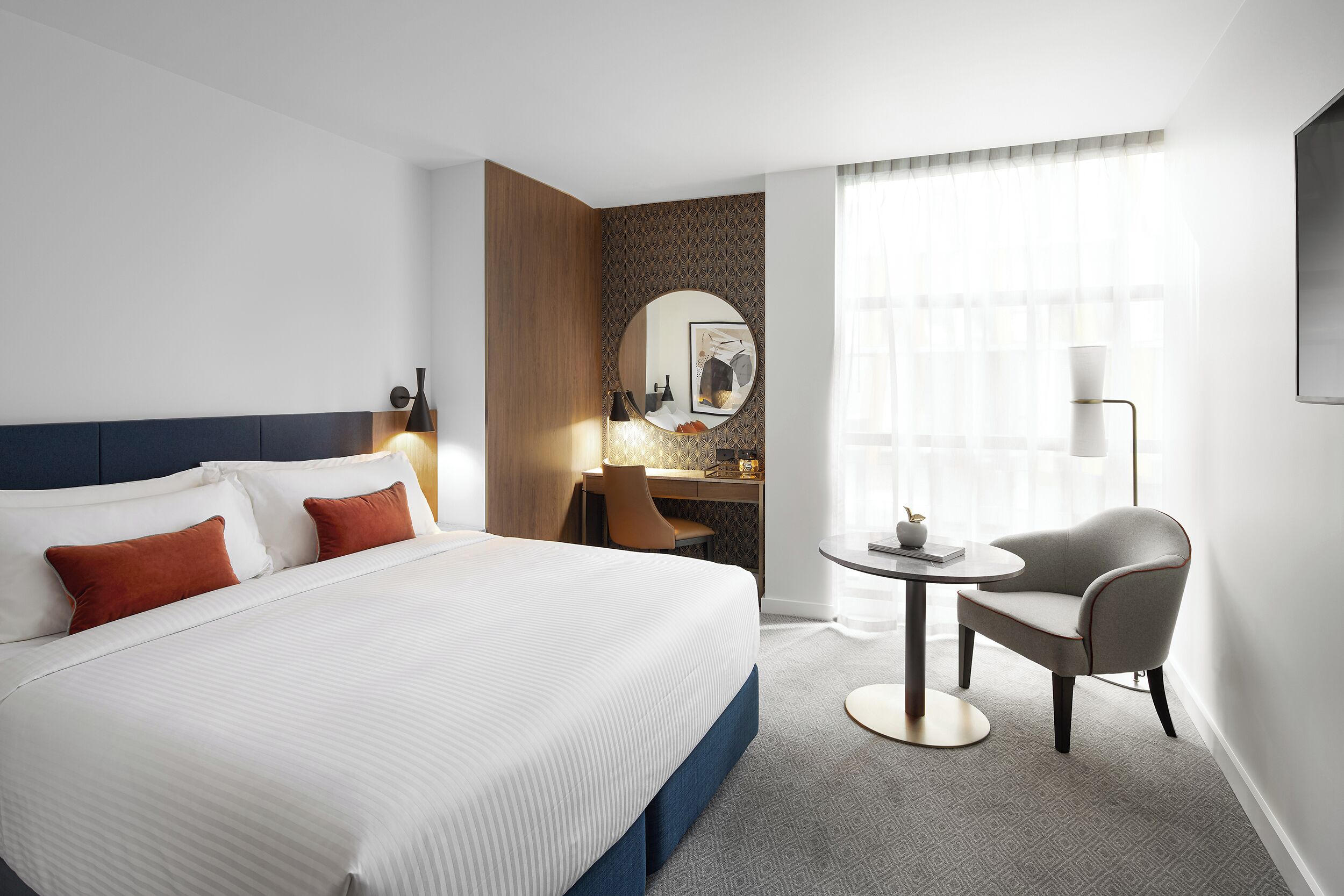 Una habitación de hotel con una cama grande, un escritorio, una silla y una mesa redonda.